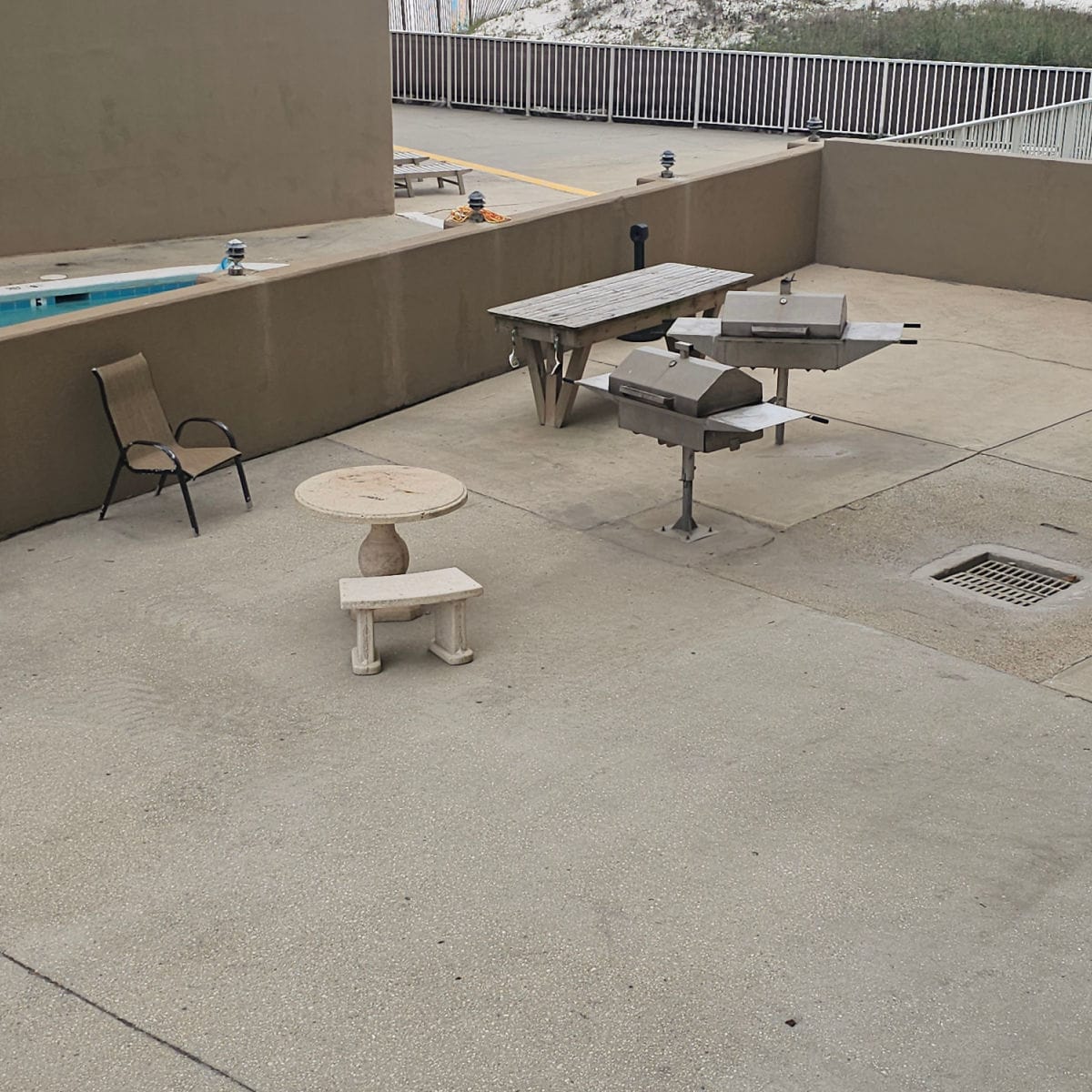 looking down over a barbecue area with two charcoal grills, a table, and small table and bench