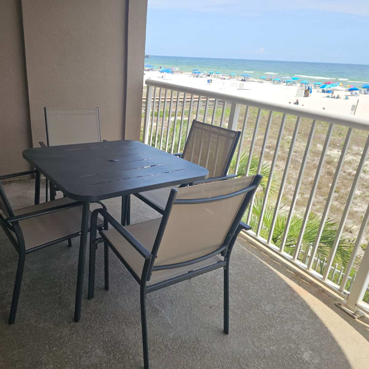 outdoor table and chairs on a balcony looking out to the beach