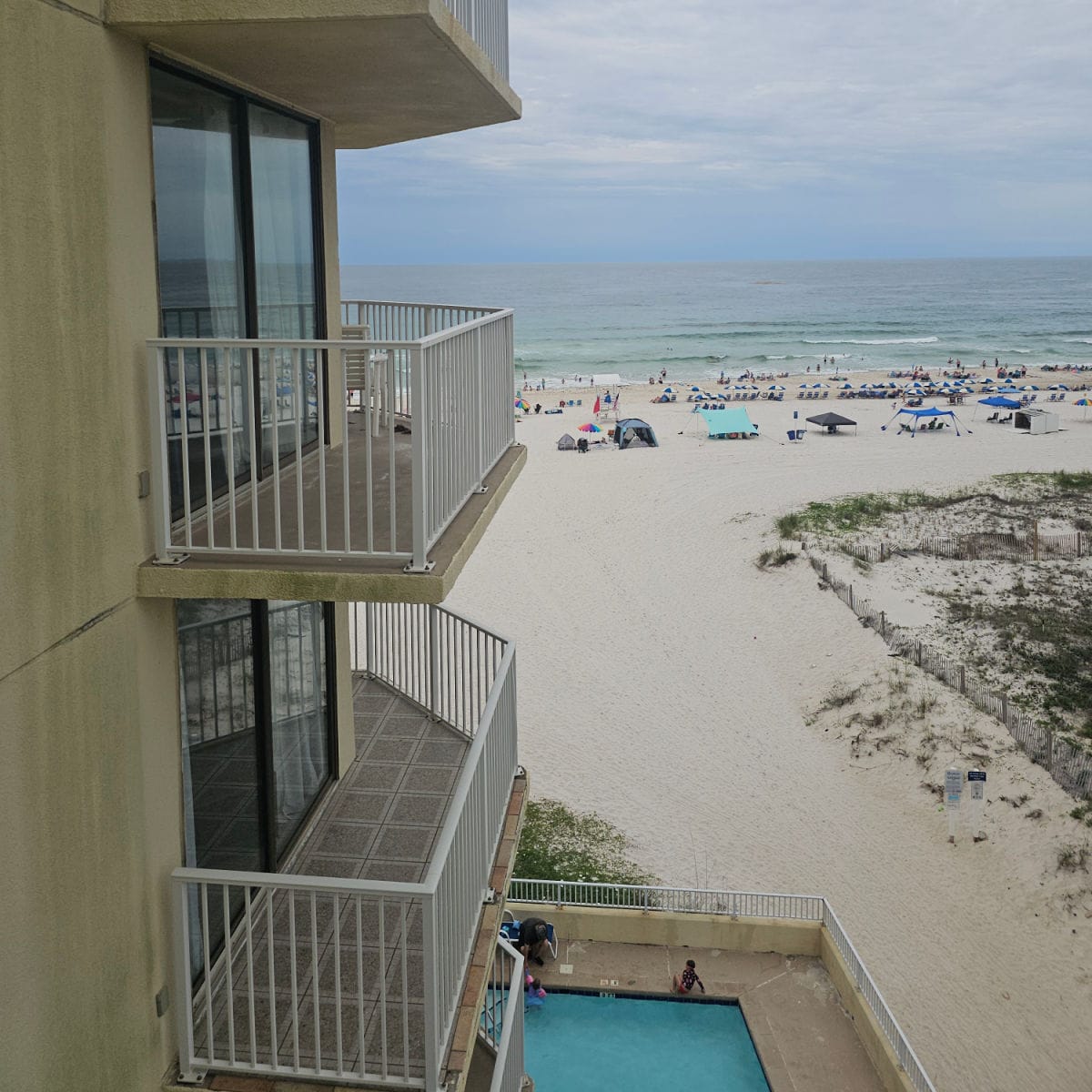 Looking at the side of the Whaler building with two balconies and then out to the sand and Gulf Waters, outdoor pool below