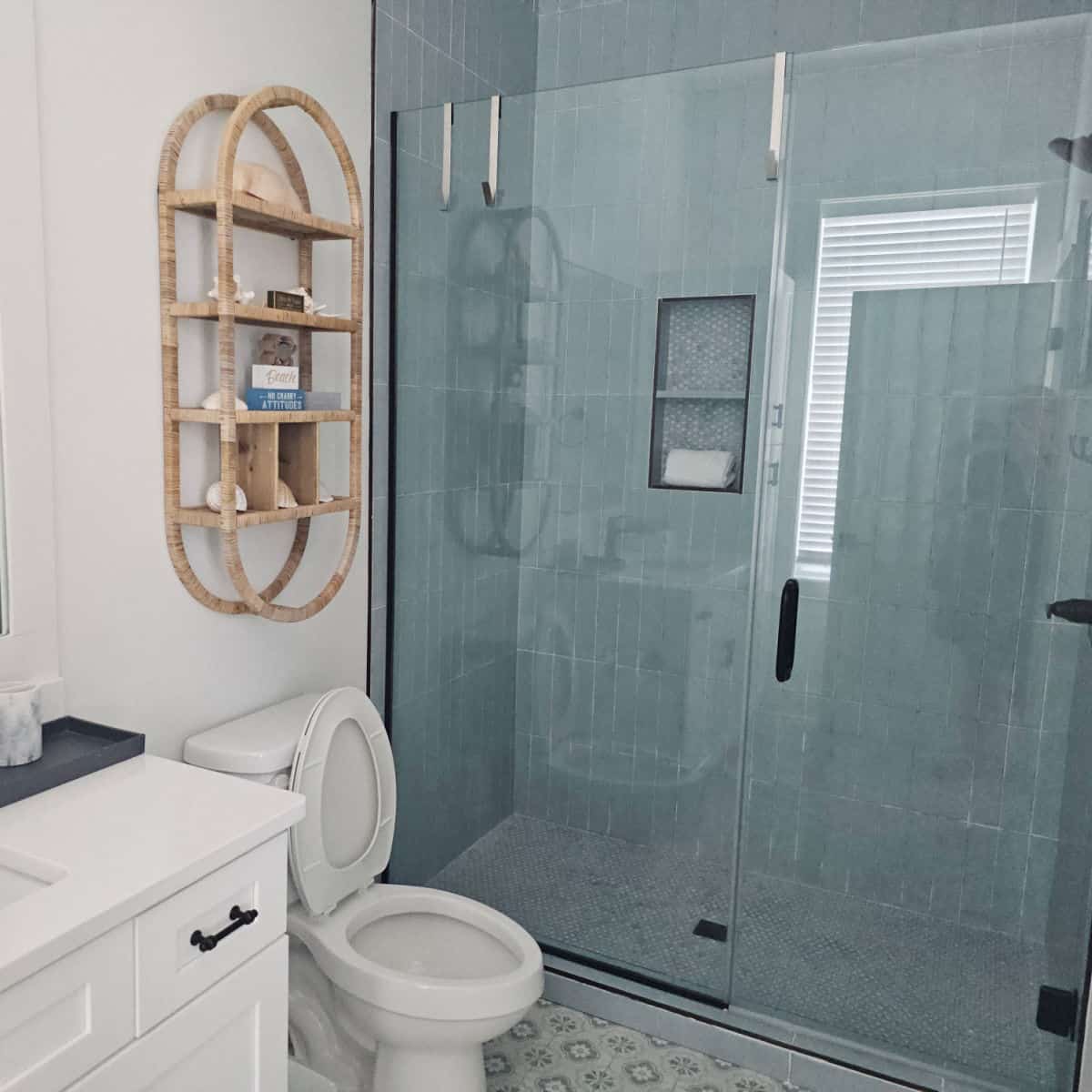 bathroom with walk in shower, rattan shelf with shells on it