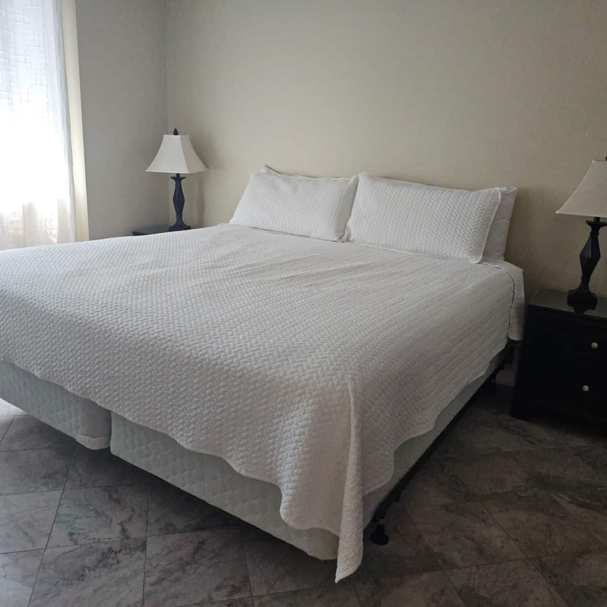 king size bed with white linens and pillows, two nightstands with lamps