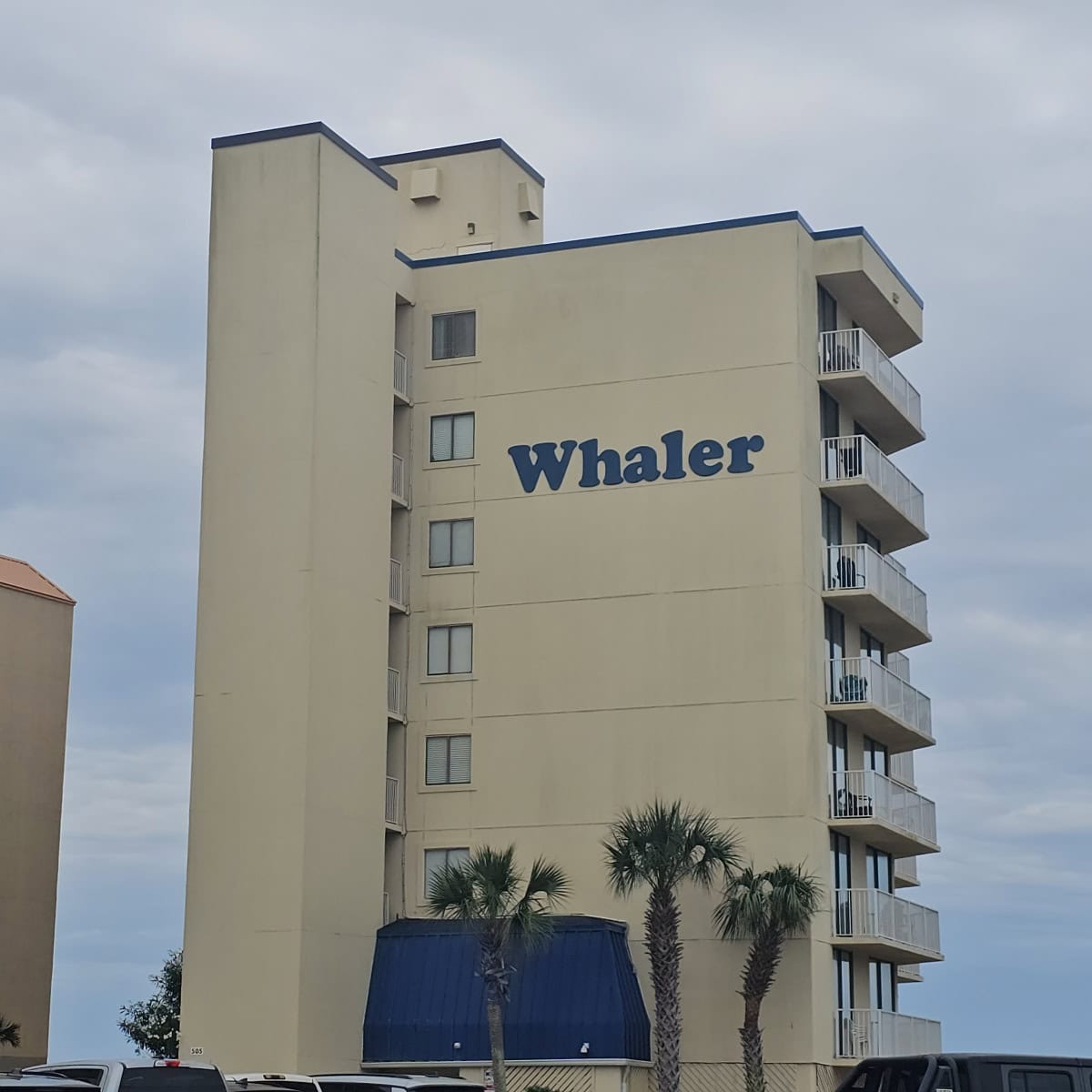 Whaler sign on the side of a tan building with a small blue awning at the bottom