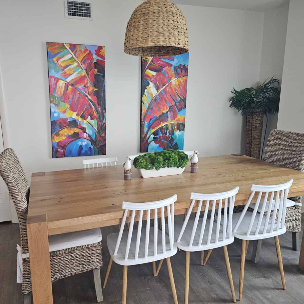 Dining room area with white chairs and brown chairs, art on the wall