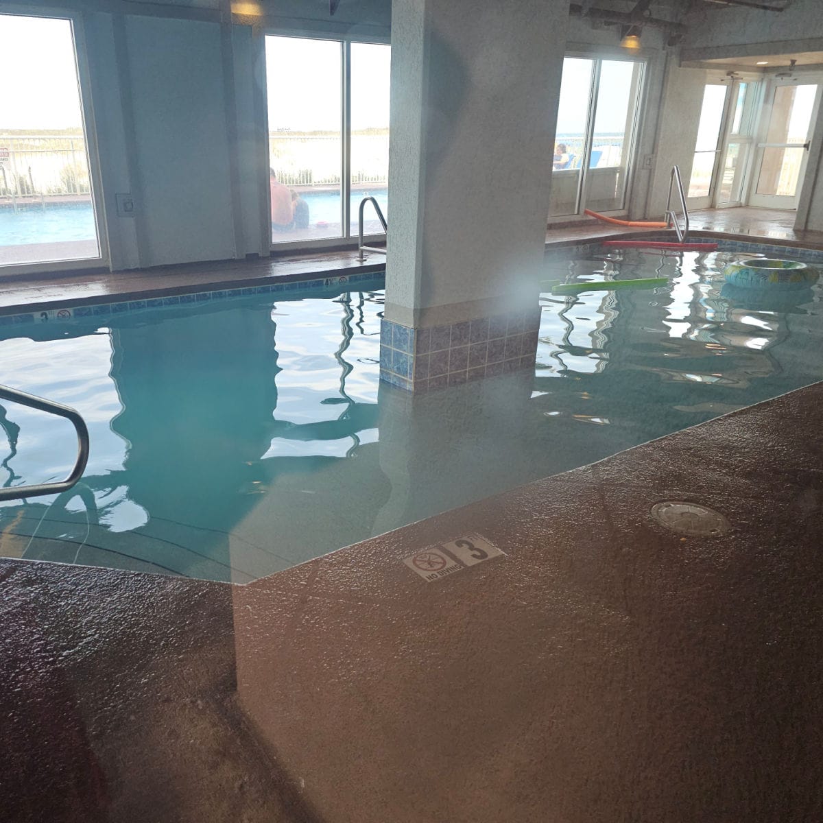 indoor pool with an inner tube and pool noodles floating in the water