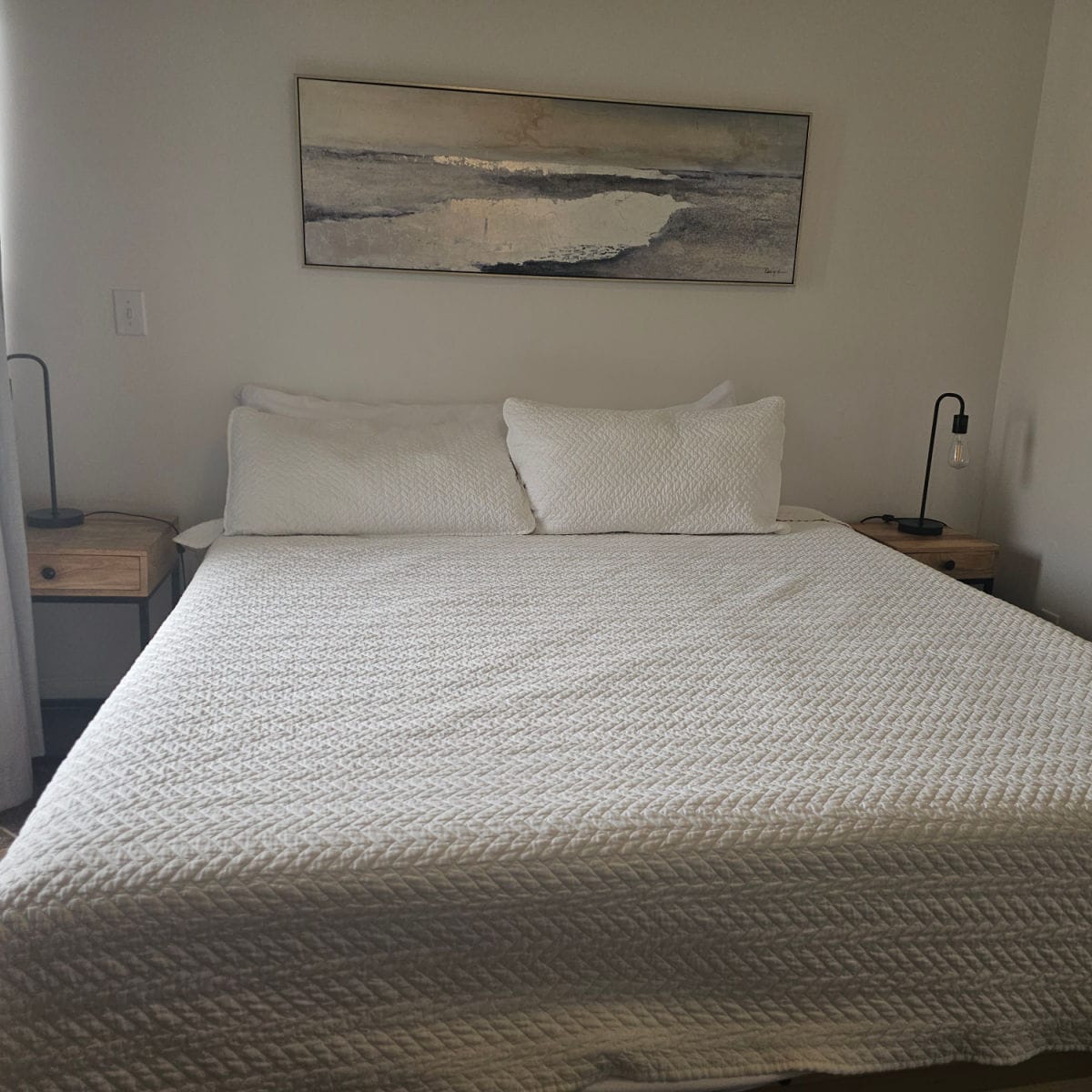 bedroom with white linen covered bed ,art over the bed