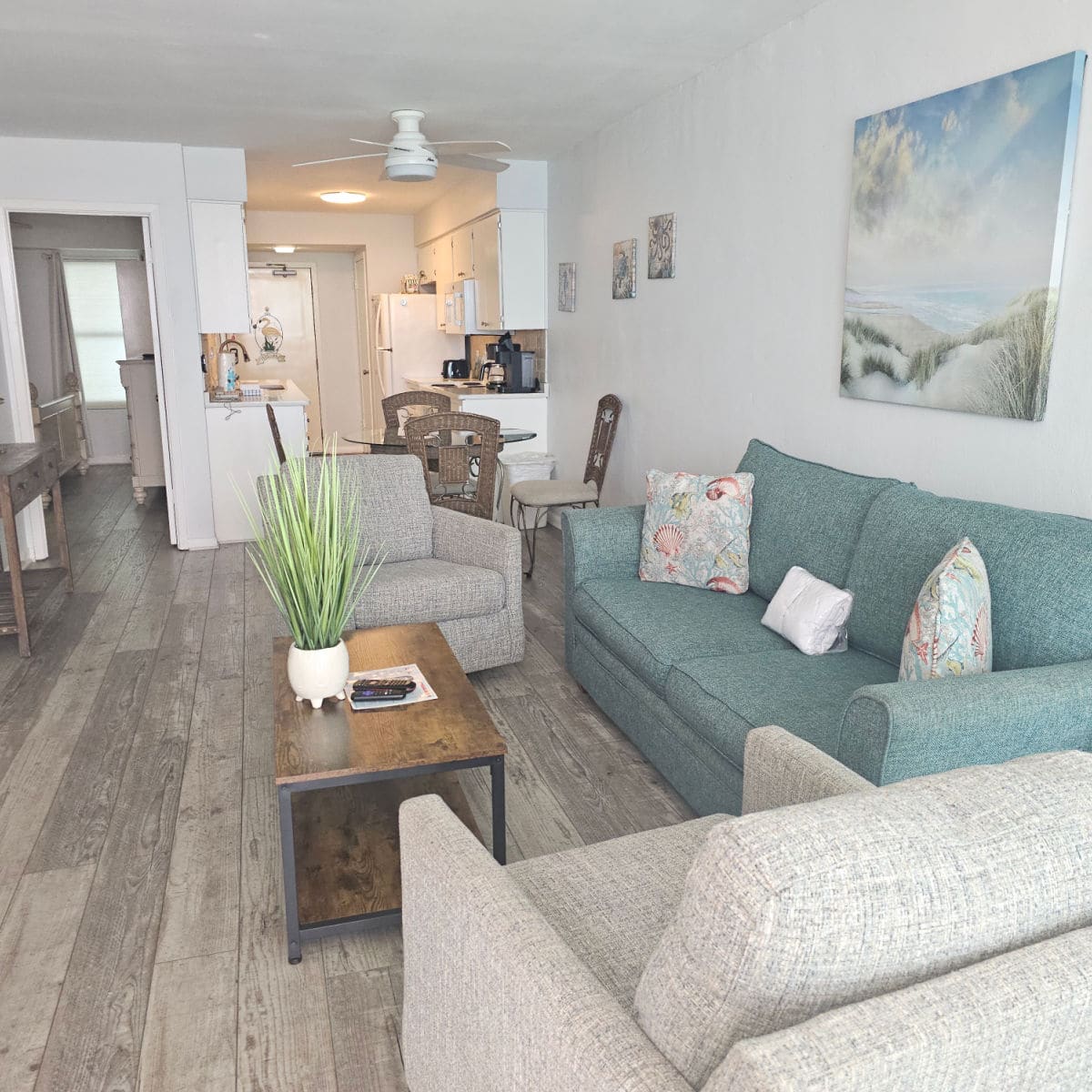 living room with cream chair, green couch, with canvas art over the couch, looking down to the kitchen