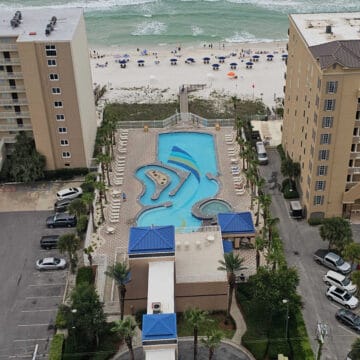 looking down over two buildings with an outdoor pool and mini lazy river and then the beah