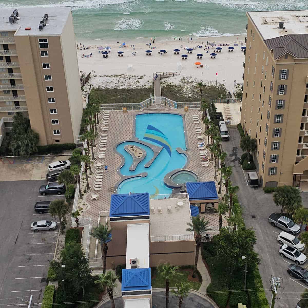 looking down over two buildings with an outdoor pool and mini lazy river and then the beah