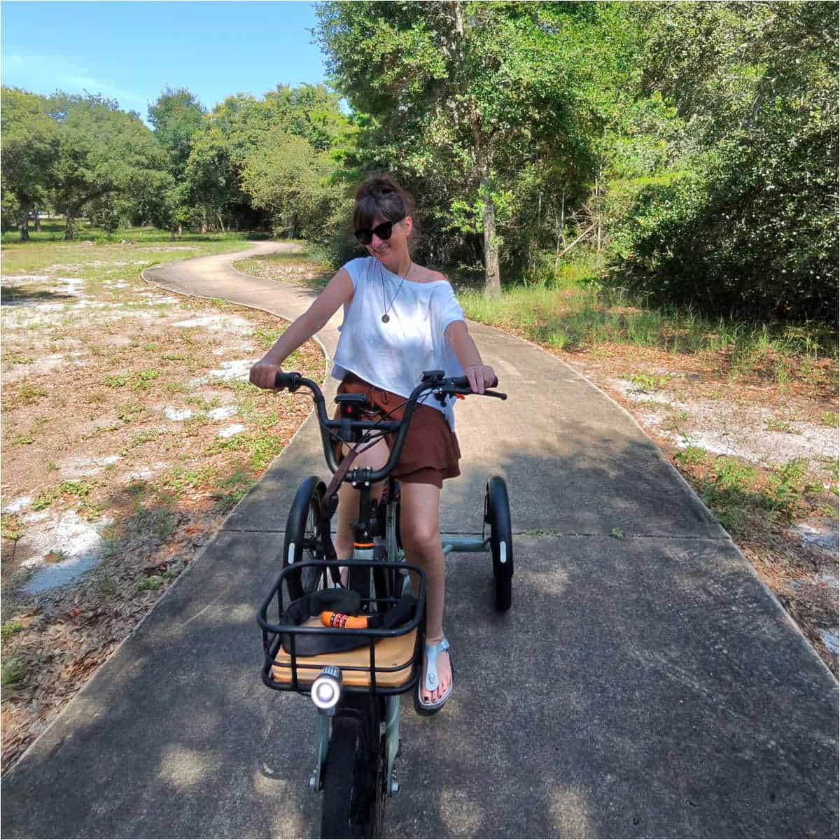 female in a white shirt and brown shorts on an e-trike