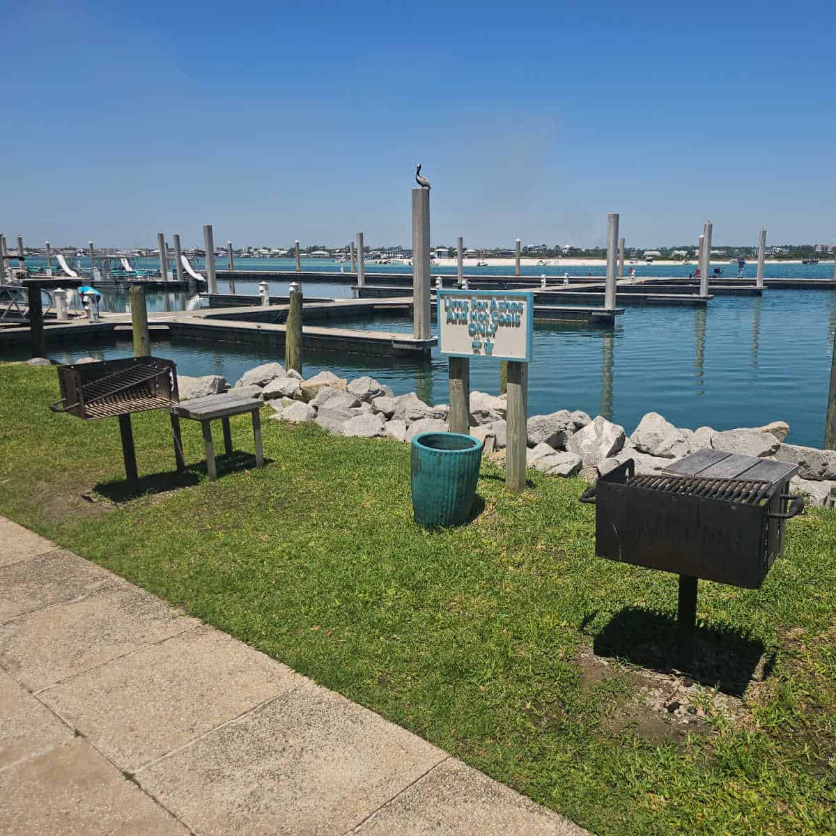 barbecue grills with water and marina in the background
