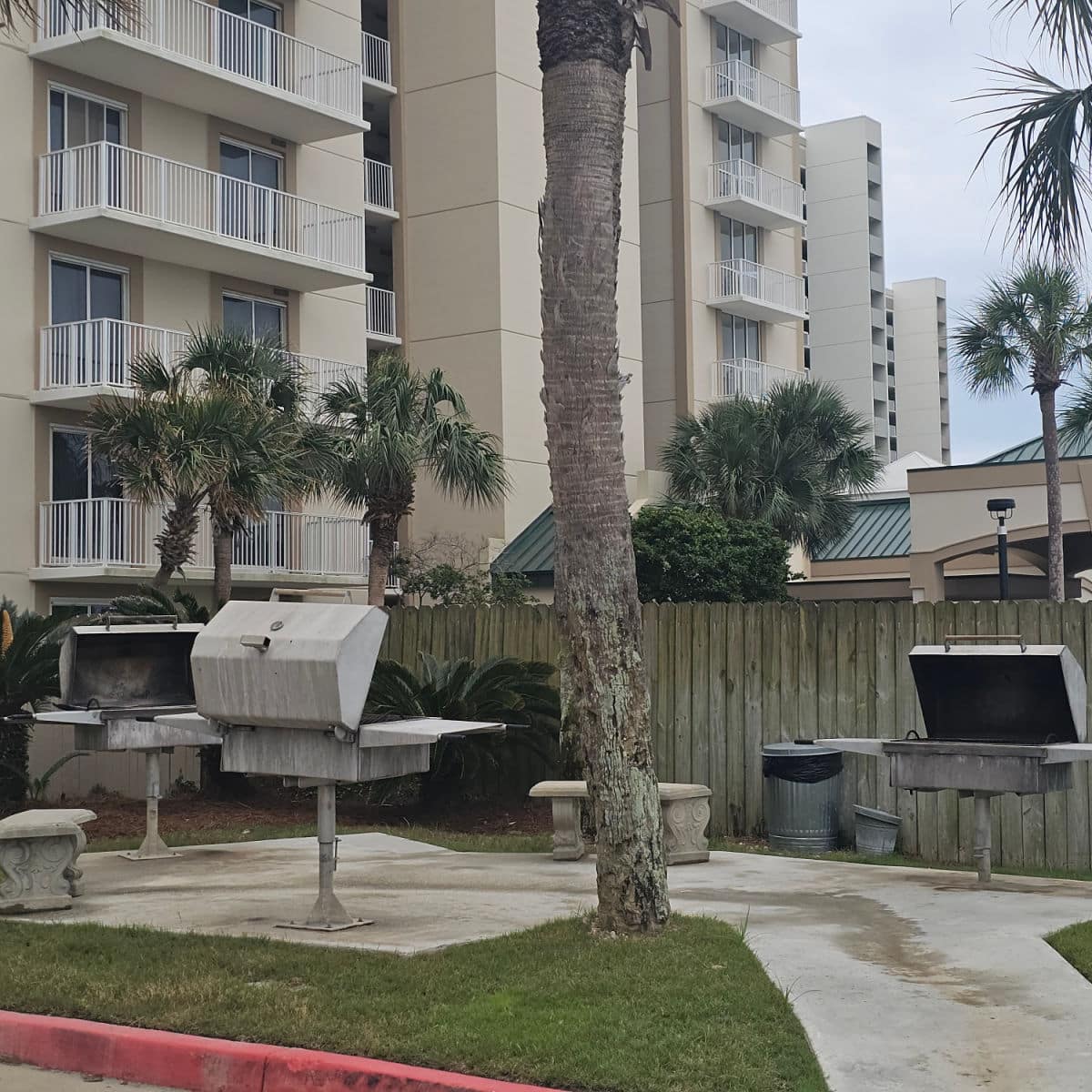 bbq area with the trunk of a palm tree in the middle, building in the background