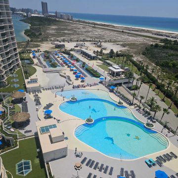 looking over a pool deck with multiple pools, lazy river, and the Gulf in the background