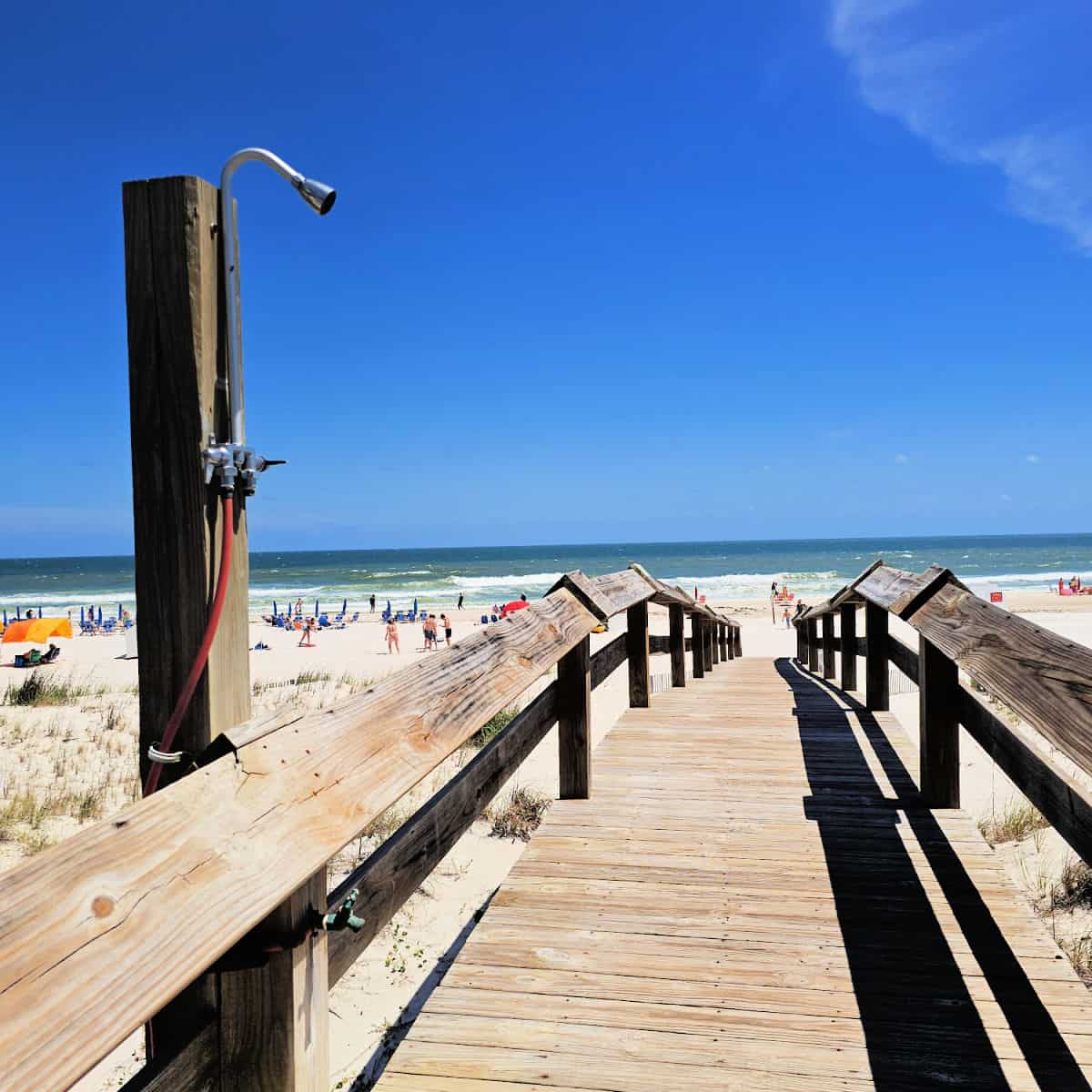 wooden boardwalk with outdoor shower leading to the sand and Gulf Waters
