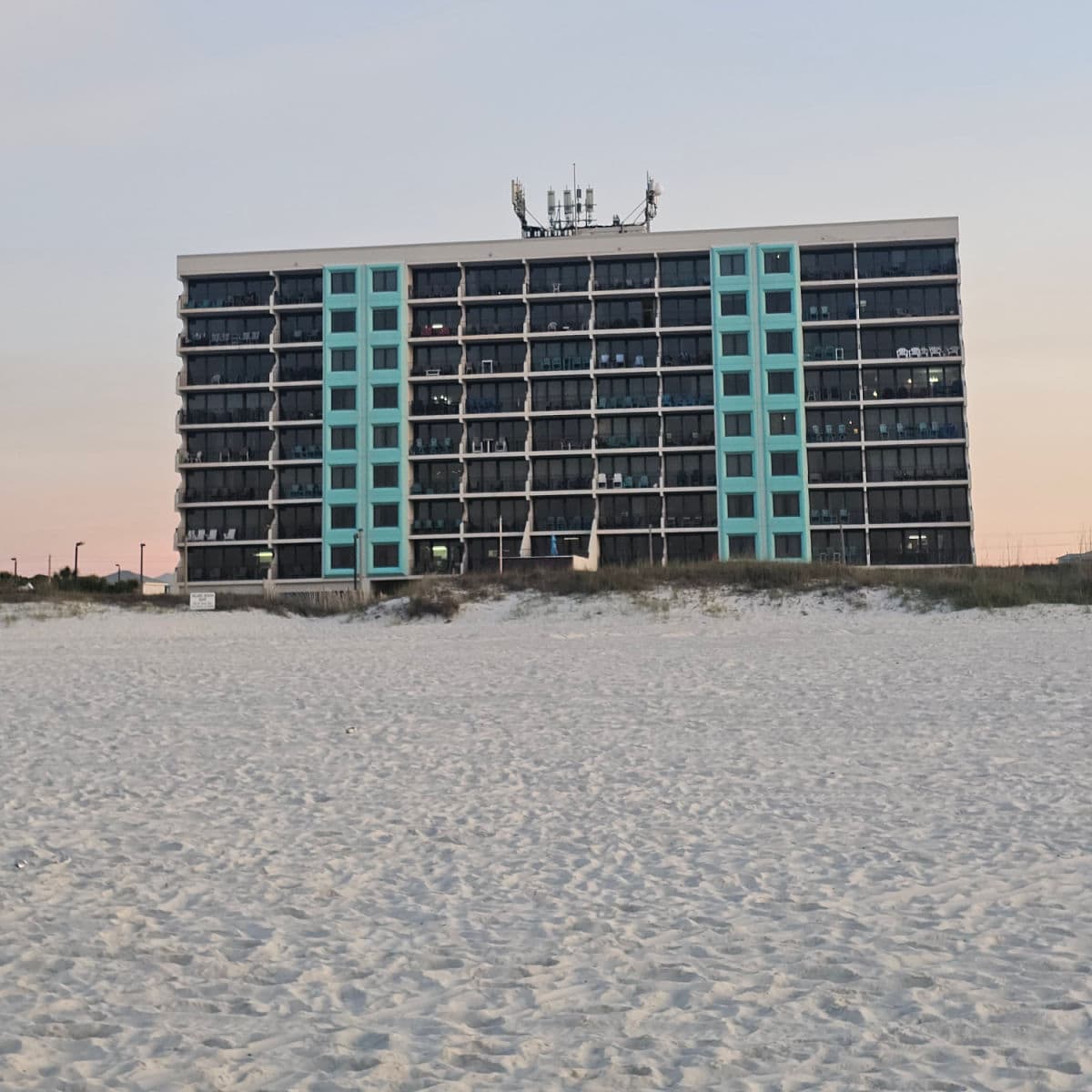 Island Winds east exterior with turquoise lines down two sections of the building, balconies with chairs