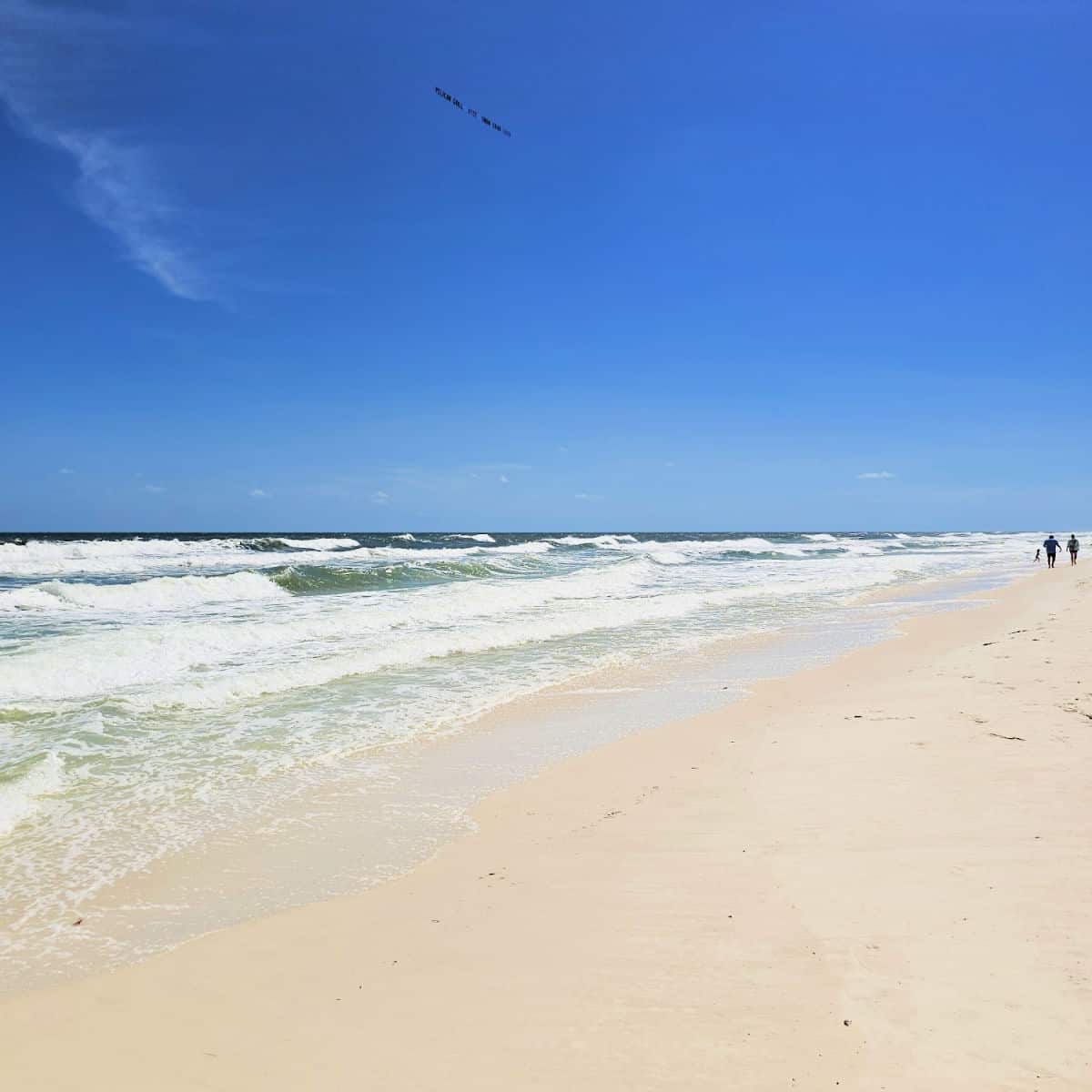 Gulf waters with waves and people walking along the edge