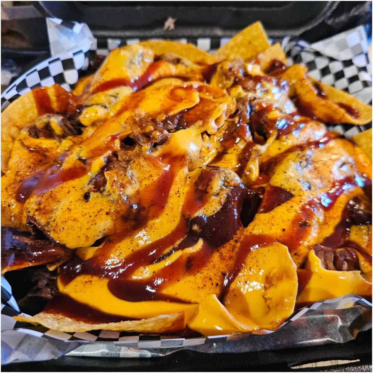 container of nachos loaded with sauce and cheese