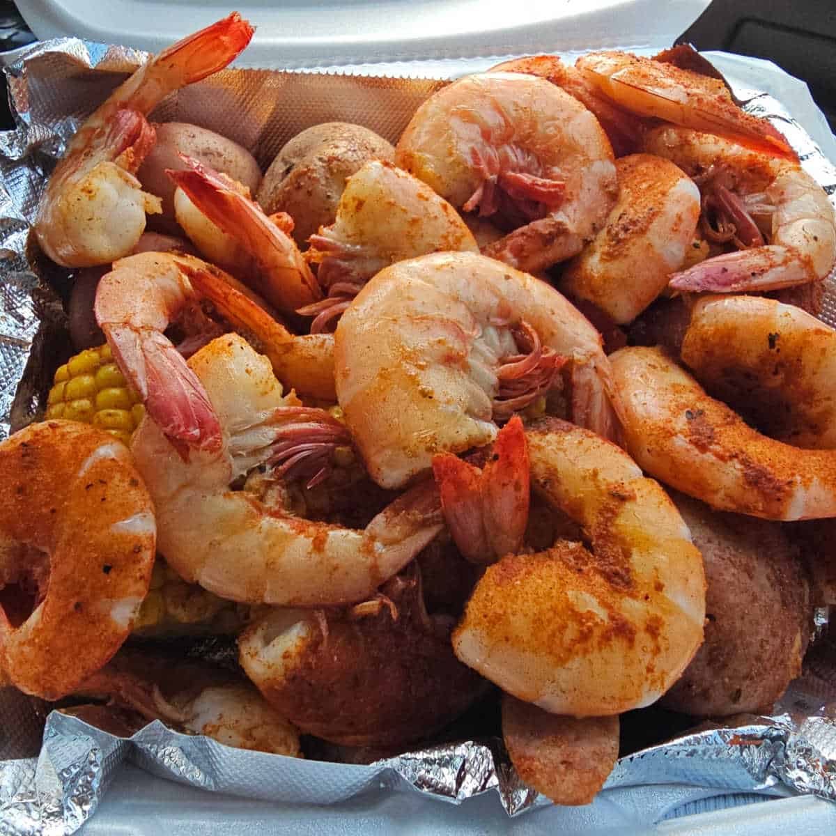 shrimp, corn, and seasoning in a foil lined container