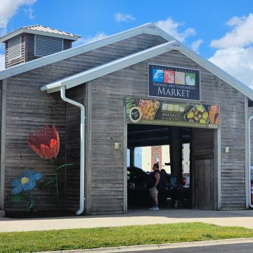 Coastal Alabama Farmers and fishermens market sign on a brown open building with artistic flower art on the side