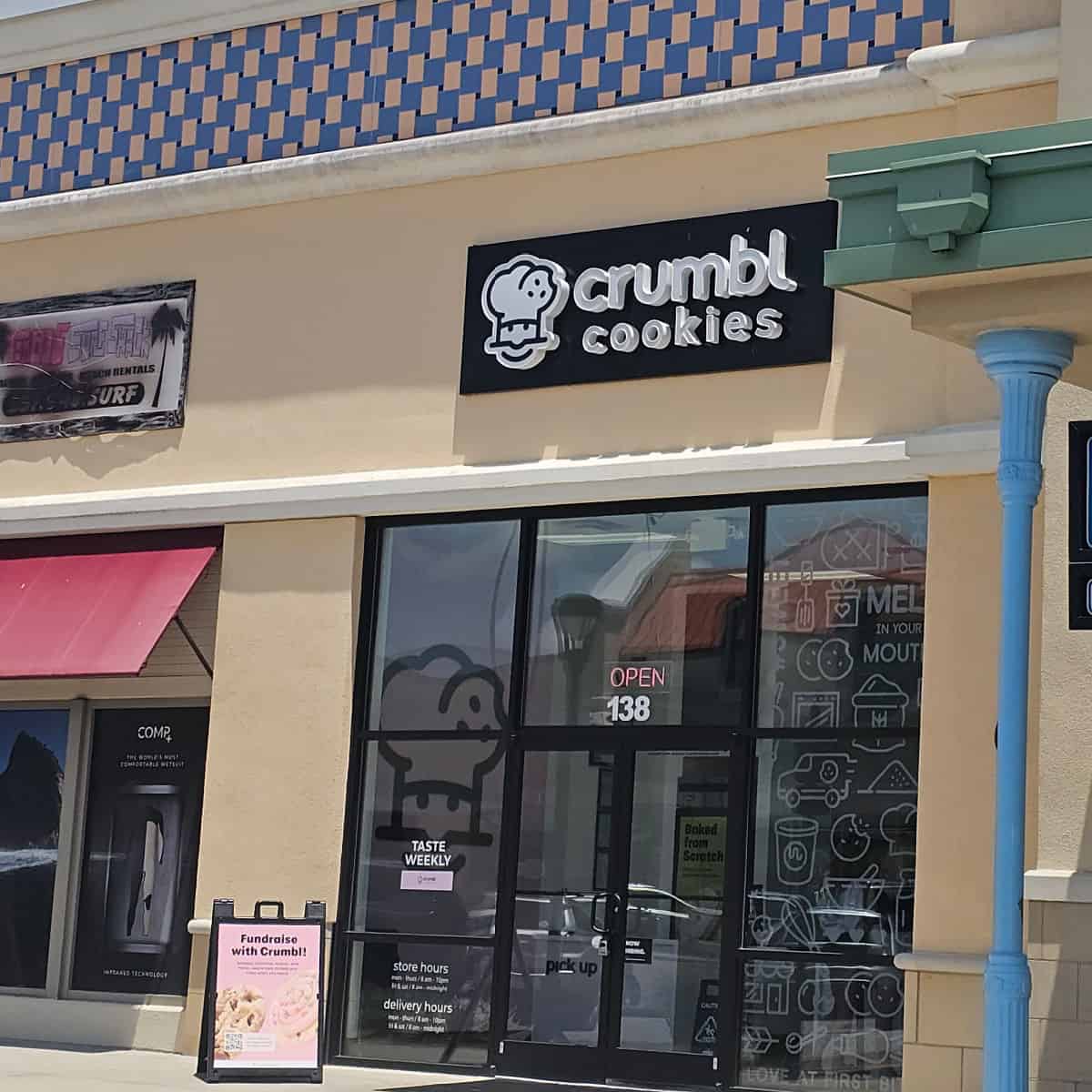 Crumbl Cookies sign above the glass door entrance to the bakery