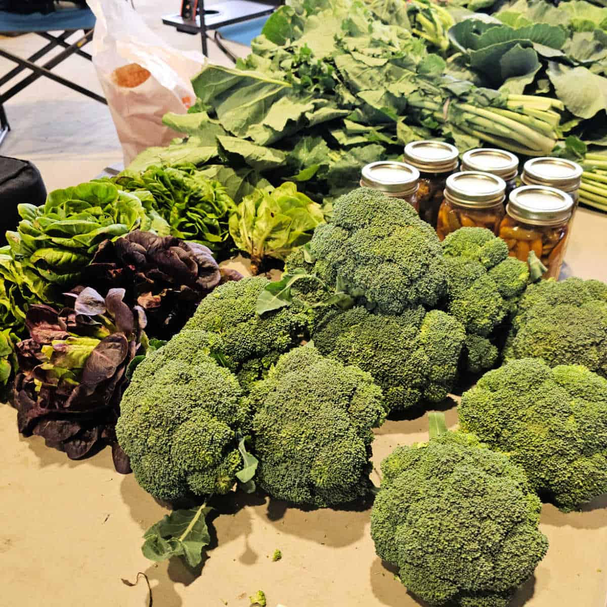 fresh vegetable on a farmers market table with broccoli, lettuce, kale, and more