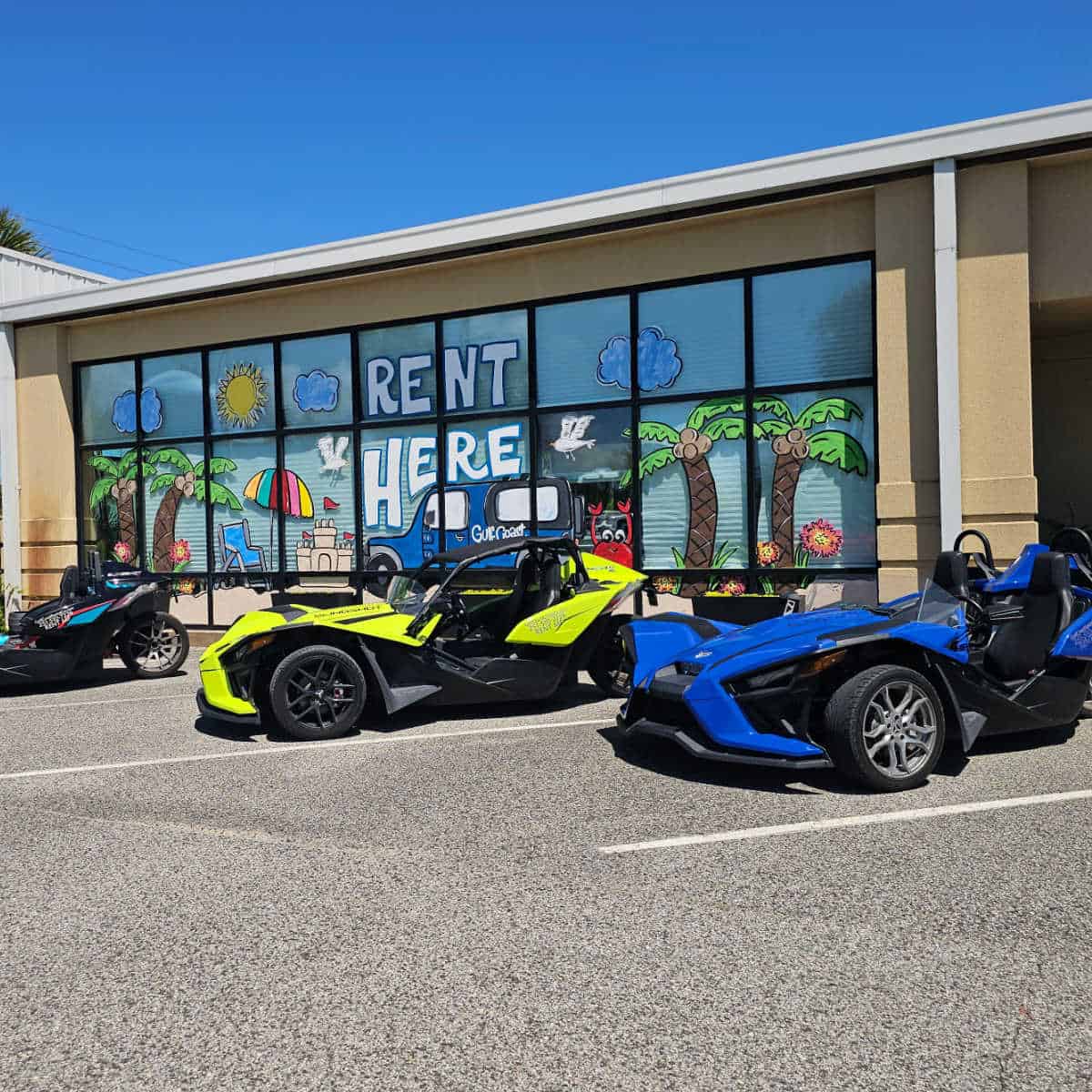 Blue and green Slingshots lined up in front of a window painted with Rent Here