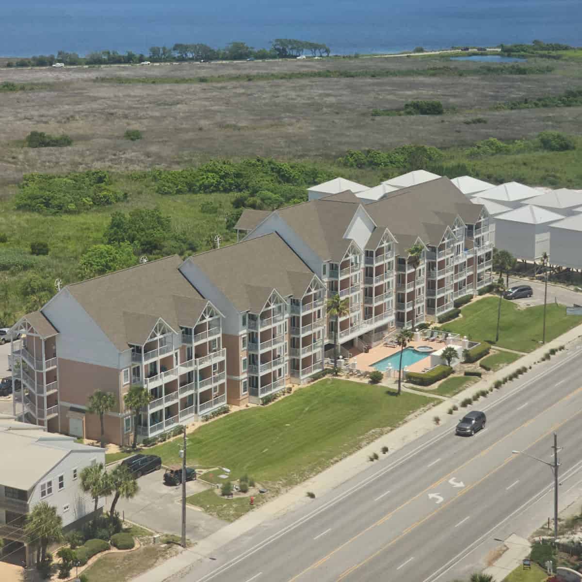 Looking over the Grand Beach Resort building and pool with park lands behind the building