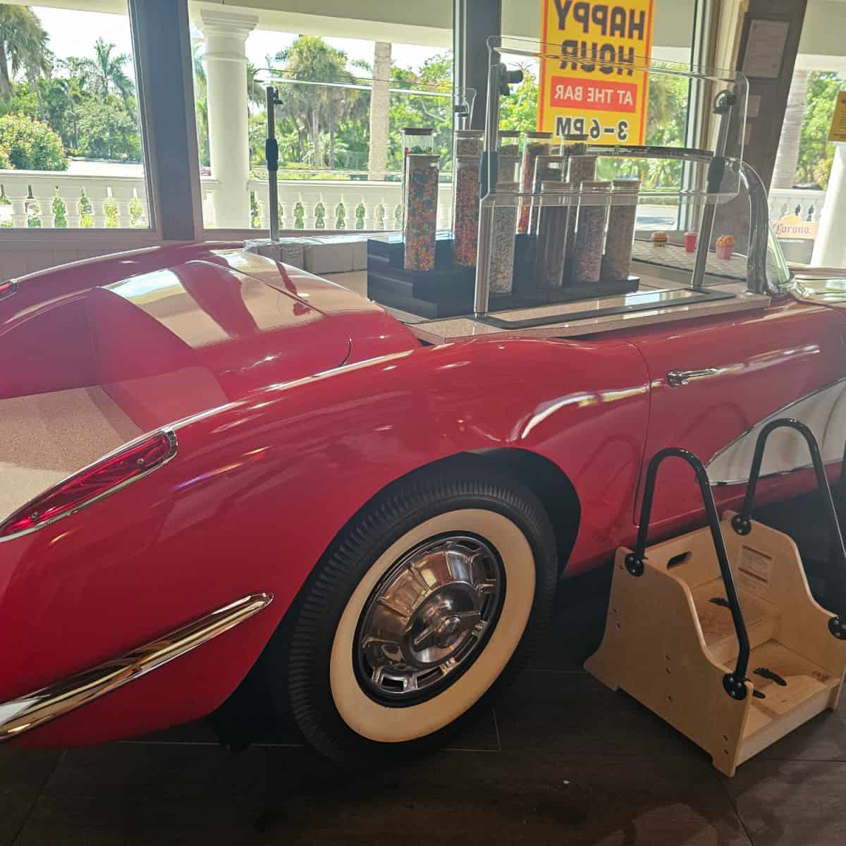 classic red and white sports car with steps up to containers of ice cream toppings