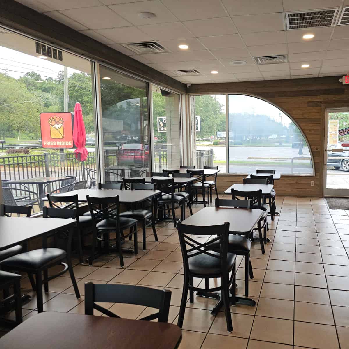 Fries inside restaurant with tables and chairs in a row, Fries Inside sign outside the window
