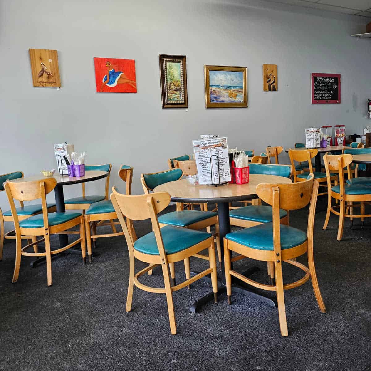indoor seating with tables and chairs, menus on the table, art on the walls