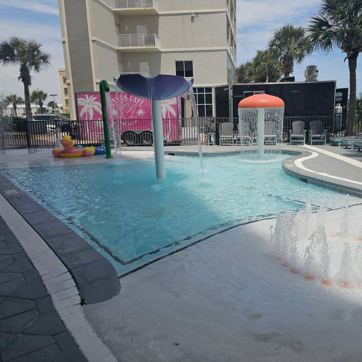 kiddie pool area with water fountains, a duck inflatable, and food trucks behind the fence.
