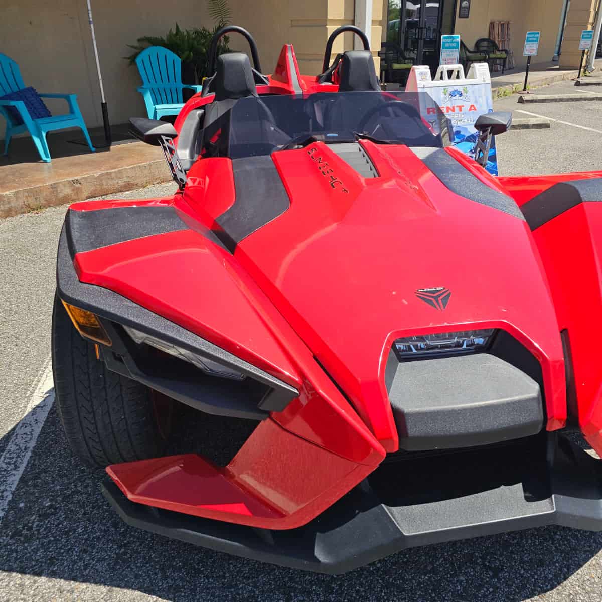 Red Slingshot with a couple of signs and Adirondack chairs in the background