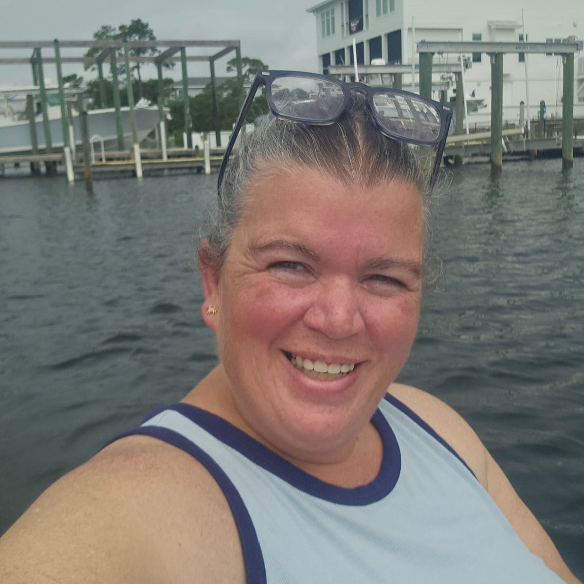 Tammilee smiling on the water with houses and boats behind her