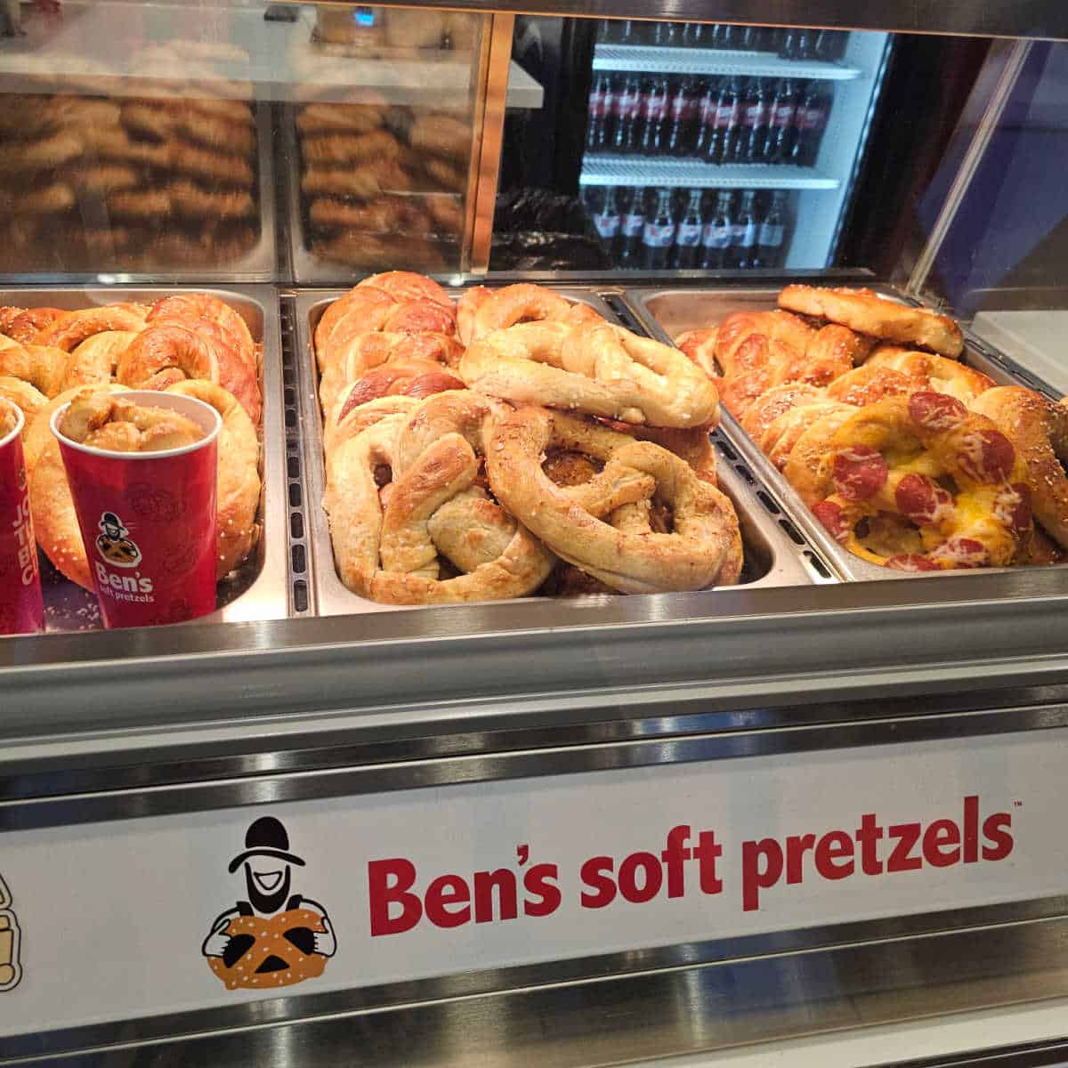 Ben's Soft Pretzel sign below three trays of pretzels behind glass