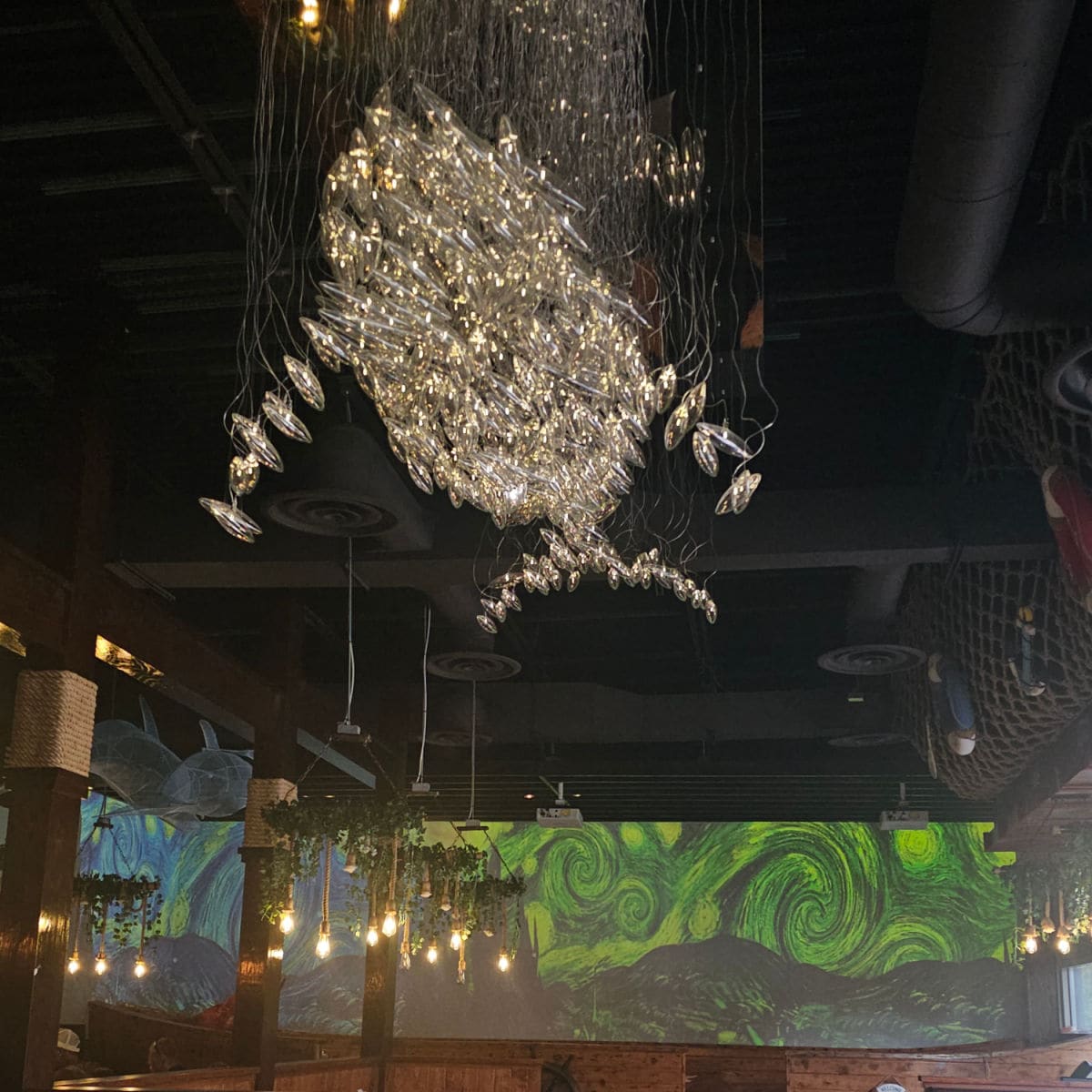 Whale light hannging from the ceiling in Miso Seafood, large screen in the background with green swirls on it