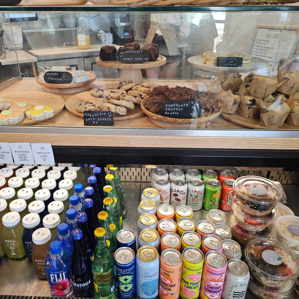 bakery case with cookies and muffins above a cooler case with drinks and acai bowls