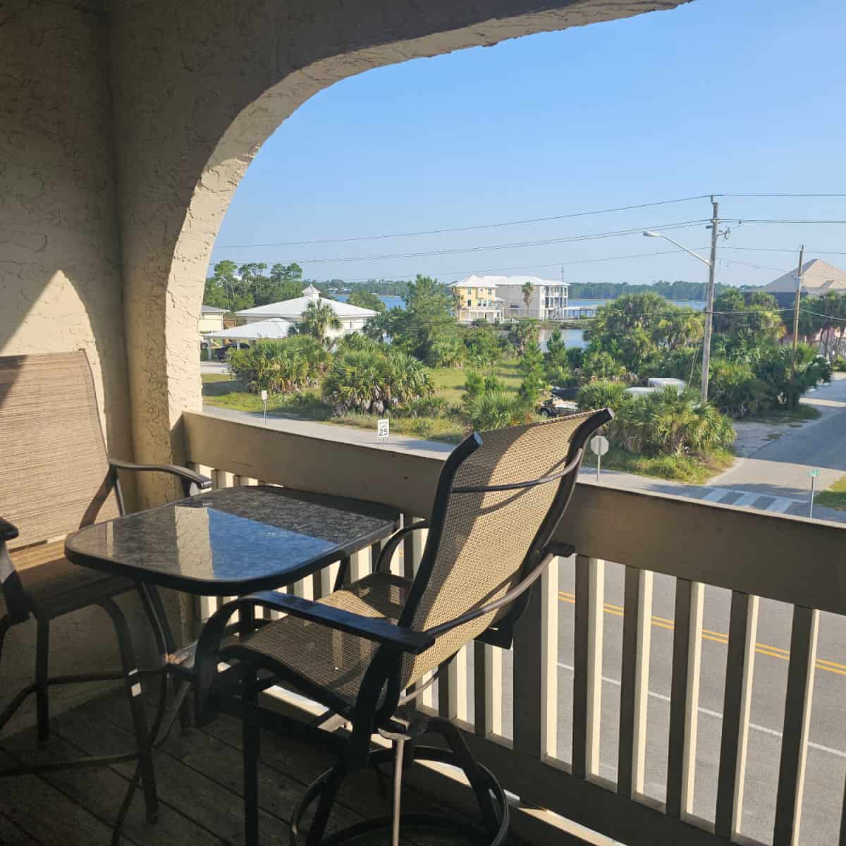 Balcony with table and chairs looking out towards houses and Little Lagoon
