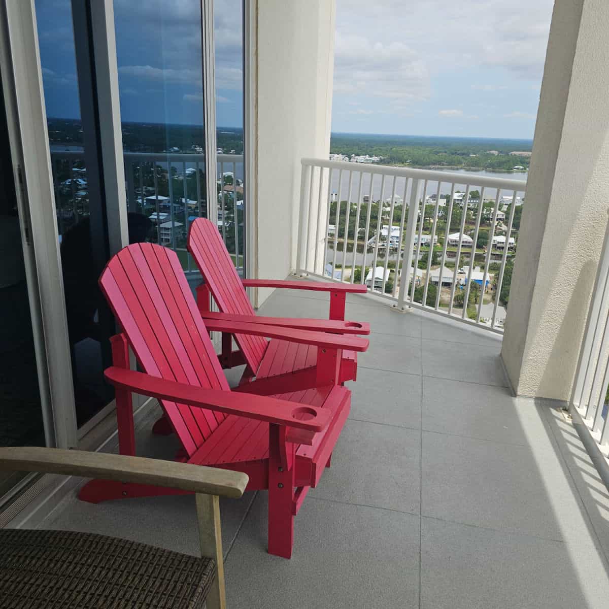 Red adirondack chairs on a balcony with views of little lagoon in the background