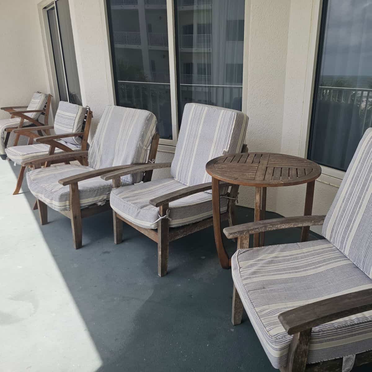 balcony with lounge chairs with blue and white striped cushions and a wooden table