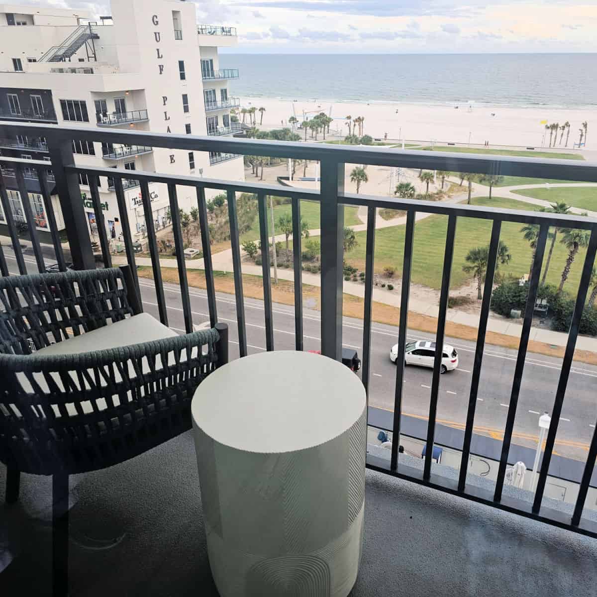 Balcony with a chair and table looking across the street to Gulf Place building and the beach with Gulf waters