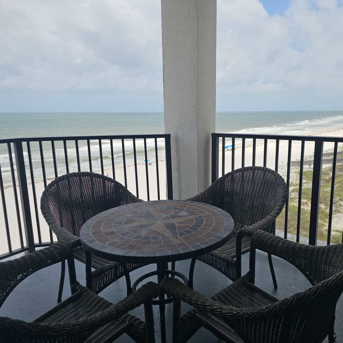 circle table on the balcony with four chairs, looking out the to the Gulf waters and white sand beaches
