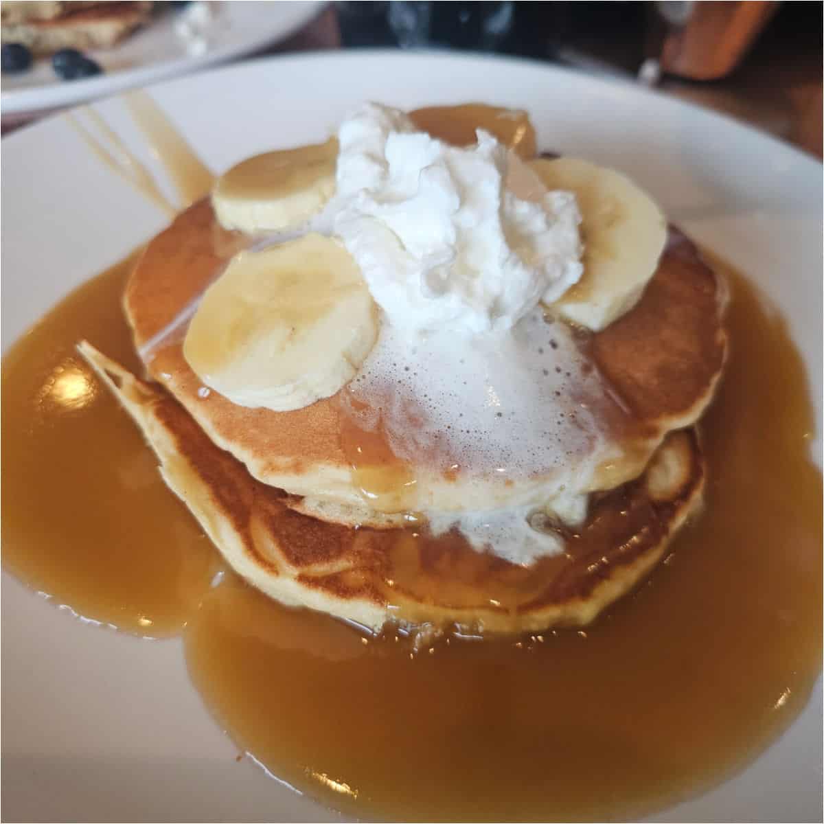 pancakes covered in sauce with bananas and whipped cream
