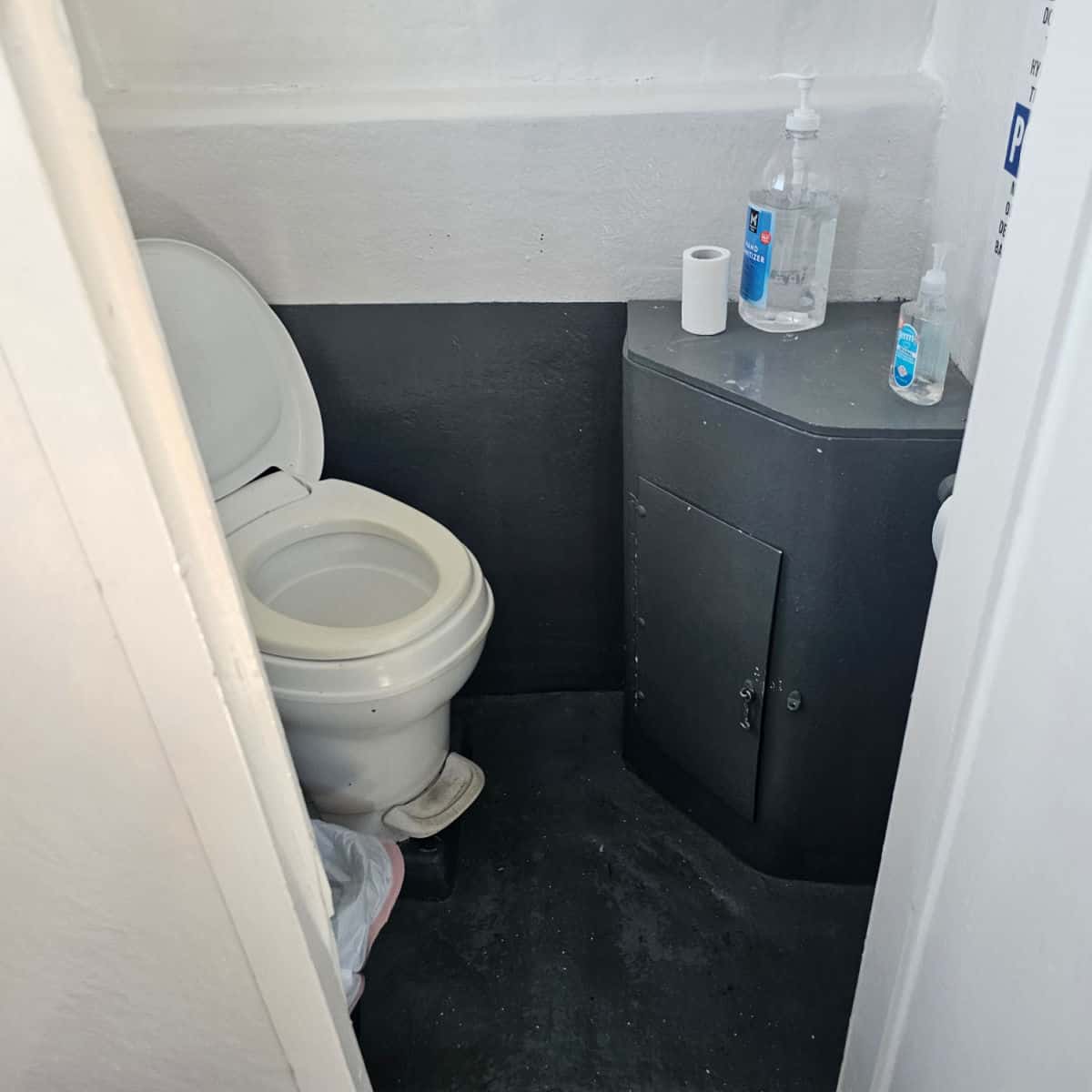 boat bathroom with a toilet, small cabinet with hand sanitizer and toilet paper on it