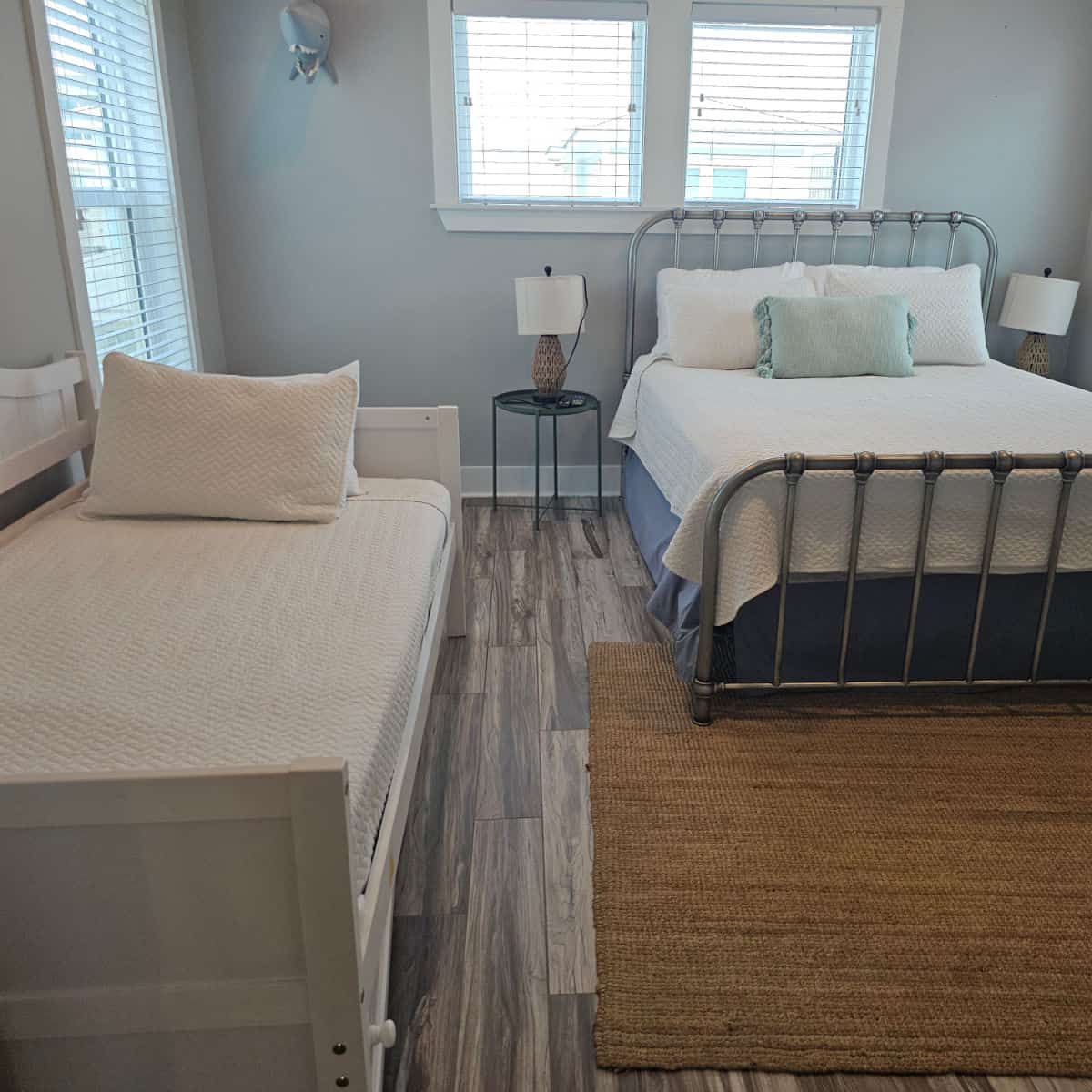 two beds in a bedroom with a couple of tables and lamps, shark head on the wall