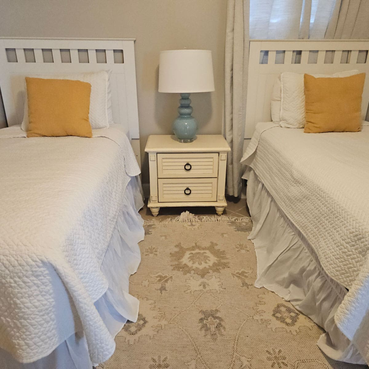 bedroom with two beds with a nightstand between them, blue lamp with a white shade