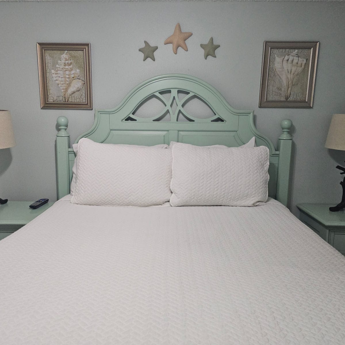 bedroom with queen bed, green headboard, and art on the wall.