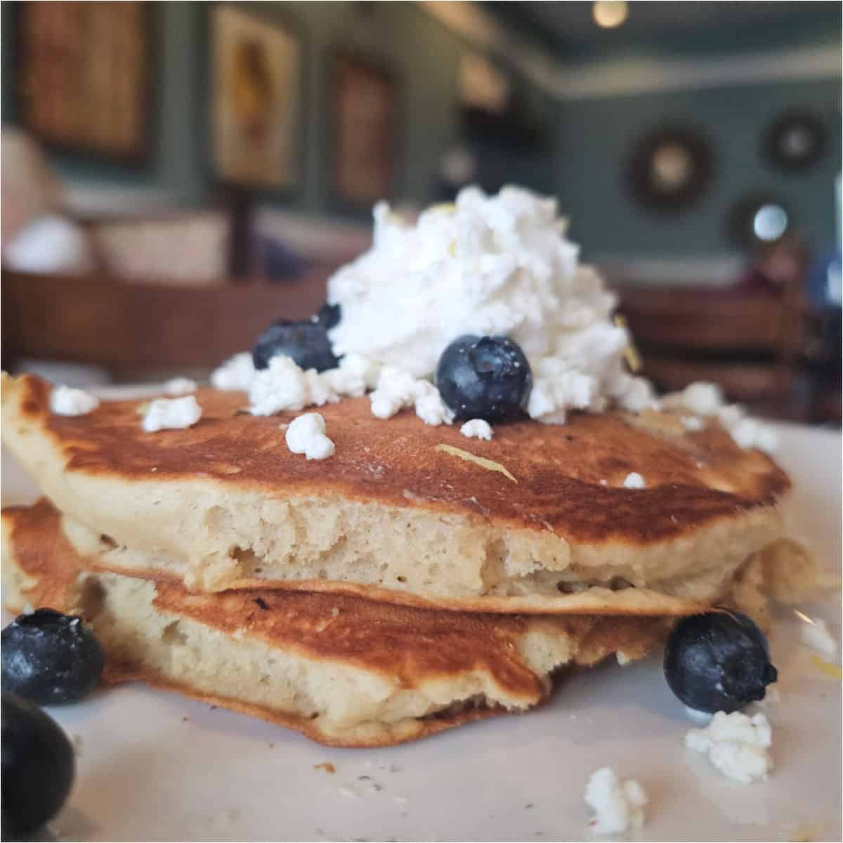pancakes with blueberries and goat cheese on a white plate