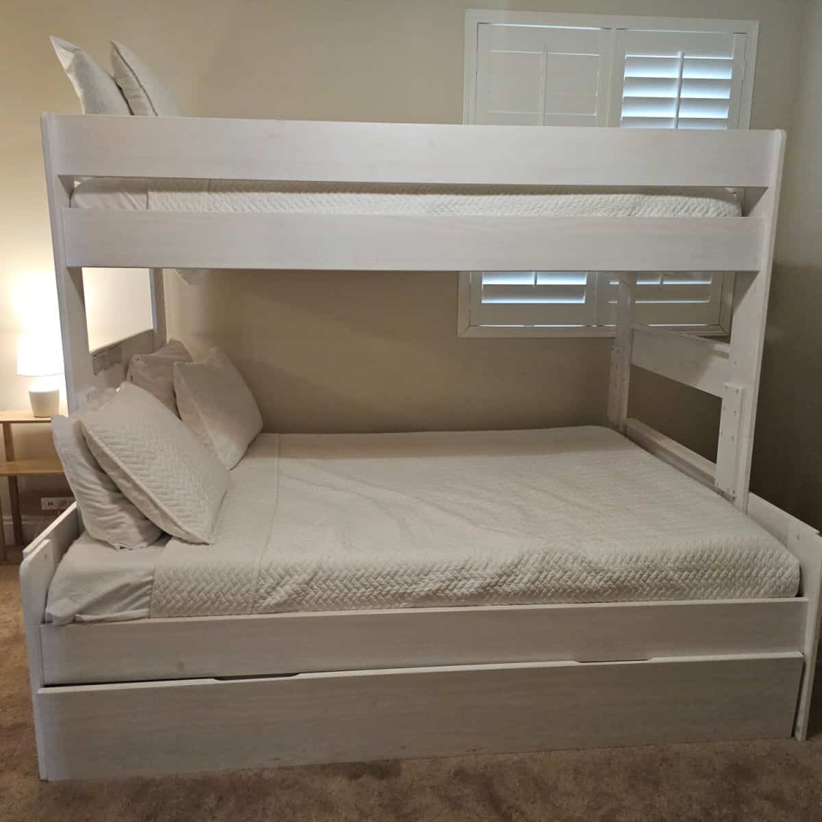 bunkbed with white covers on the beds, lamp in the corner