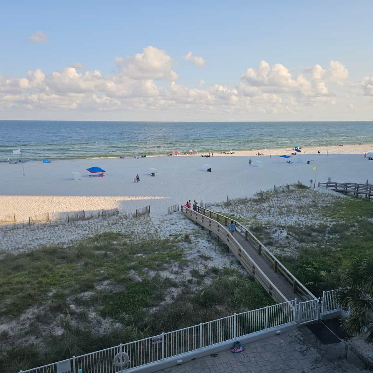 looking over sand dunes with an elevated walkway to the beach, sandy beach and then Gulf waters
