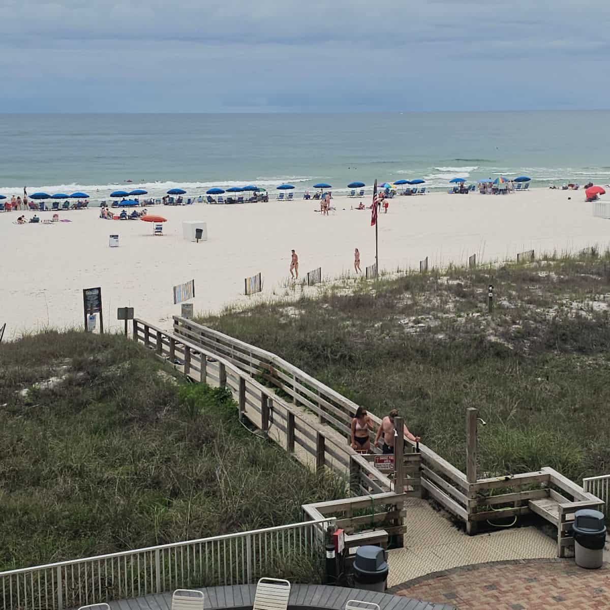 beach access walkway with sand and tents along the water