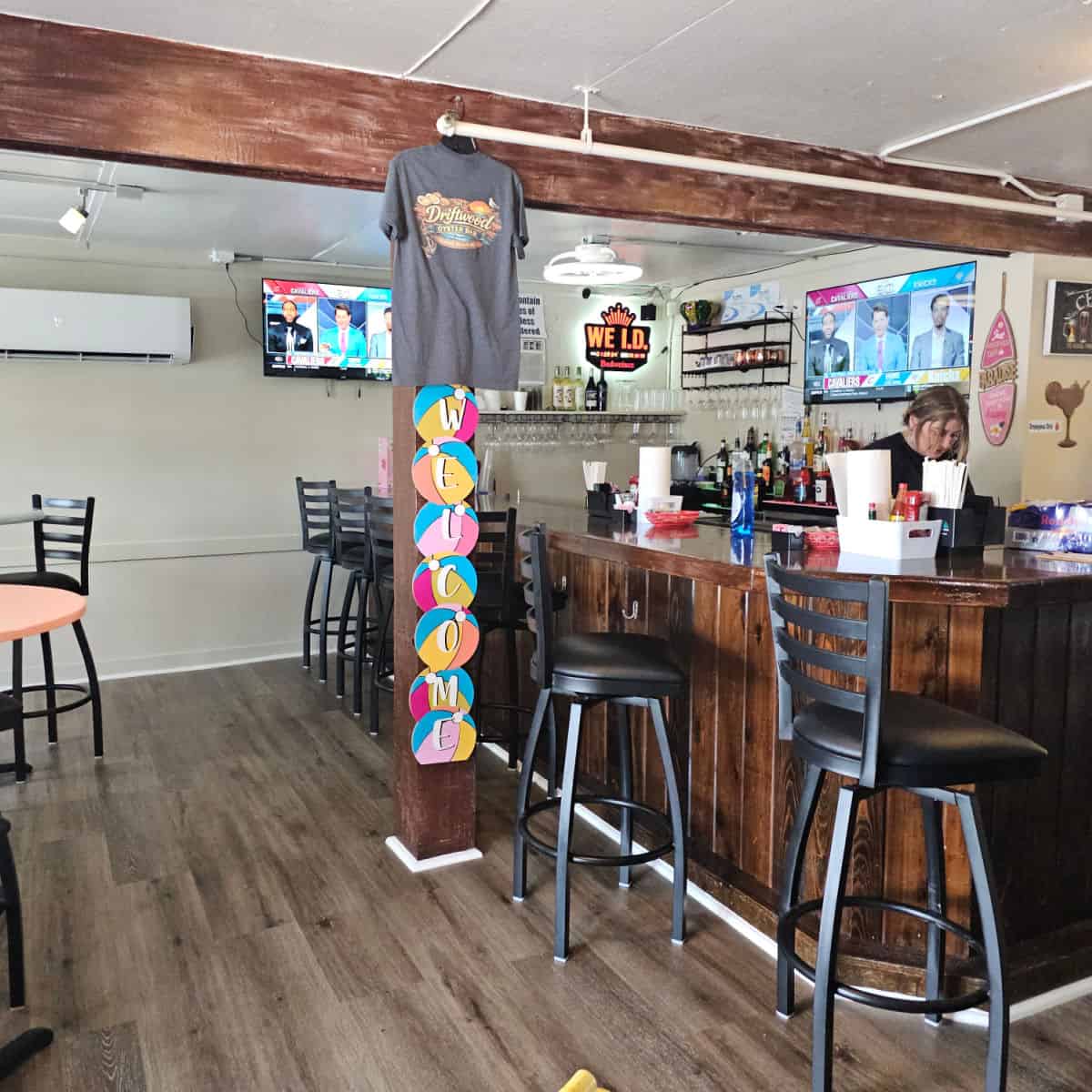 indoor bar with tall chairs, women behind the bar, tv on the back